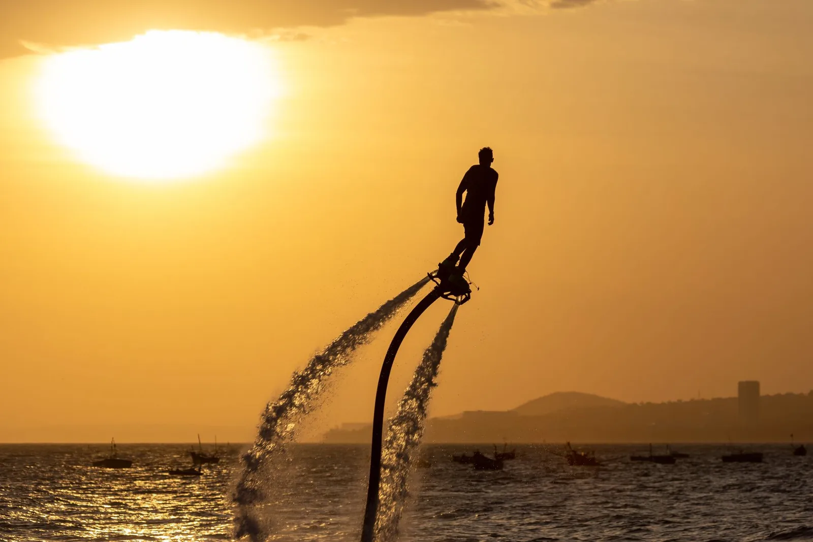 En flyboardåkare i silhuett mot kvällshimlen