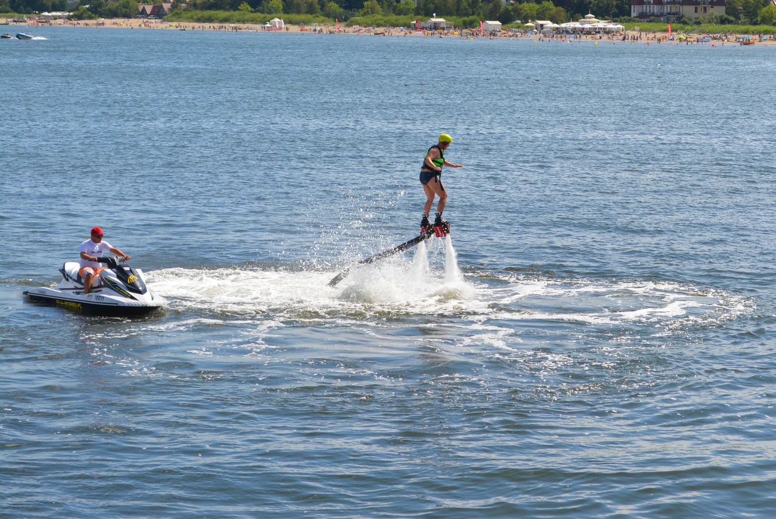 En flyboardåkare med slang och följande vattenskoter i Sopot